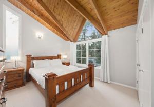 a bedroom with a wooden bed and a window at Our Glenbogle in Medlow Bath