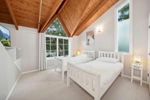 two beds in a white room with windows at Our Glenbogle in Medlow Bath
