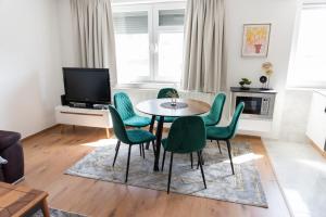 a living room with a table and green chairs at Apartment Center Korzo in Bihać