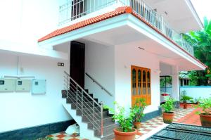 uma casa branca com uma escada e uma porta laranja em Grace Guest Home em Thrissur
