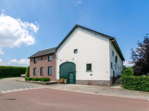a white barn with a green door next to a street at Heimerhöfkes -2 in Klimmen