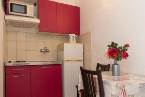 a kitchen with red cabinets and a table and a refrigerator at Apartment Zuronja 10137b in Brijesta