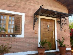 a brick house with a wooden door and a window at Casa Flor de Lis in Águas de São Pedro +5 photos