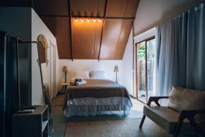 a bedroom with a bed and a chair and a window at Cabana Pitomba - Viagem Inspirada in Fernando de Noronha