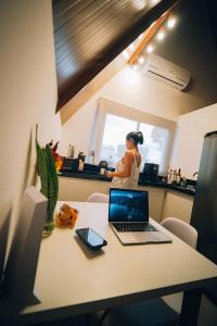 a woman sitting in a kitchen with a laptop on a table at Cabana Pitomba - Viagem Inspirada in Fernando de Noronha
