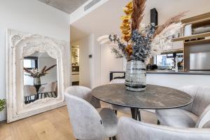a dining room with a table and chairs and a mirror at Suave Condo in Trendy PrahranSteps to Greville St in Melbourne