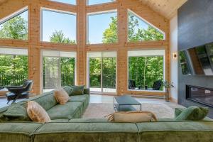 a living room with a green couch and a fireplace at Lilia Chalet Urbain de Luxe près du Mont-Tremblant in Saint-Rémi-dʼAmherst