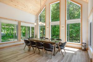 a dining room with a table and chairs and windows at Lilia Chalet Urbain de Luxe près du Mont-Tremblant in Saint-Rémi-dʼAmherst