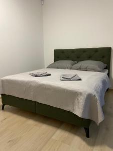a bed with a green headboard with two towels on it at AR MYKONOS oasis in Košice