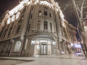 ein großes Gebäude in der Nacht auf einer Straße in der Unterkunft Hotel Venezia by Zeus International in Bukarest