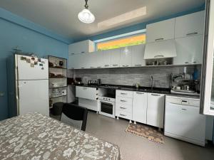 a kitchen with white cabinets and a table and a refrigerator at Royal House in Kvariati +66 photos