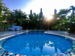 a large blue swimming pool with the sun in the background at Kejora Garden Resort Pulau Pangkor in Pasir Bogak