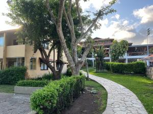 ein Baum vor einem Gebäude mit Gehweg in der Unterkunft Portal de Gravatá para até 6 pessoas - Térreo in Gravatá
