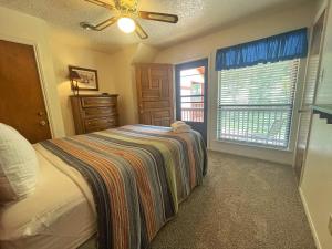 una camera da letto con un letto con una coperta a righe sopra di Valley Condo 107 - Creekside - WiFi - Hot Tub - Fireplace - Washer - Dryer - Playground a Red River