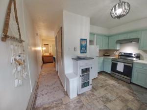 a kitchen with green cabinets and a white refrigerator at Valley Condo 108 - Skye Retreat - Creekside - Pet Friendly - WiFi - Hot Tub - Fireplace - Washer - Dryer - Playground in Red River +17 photos