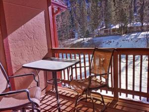 un tavolo e due sedie su un balcone con vista di Valley Condo 110 - Creekside - WiFi - Pet Friendly - Hot Tub - Fireplace - Washer - Dryer - Playground a Red River Altre 10 foto