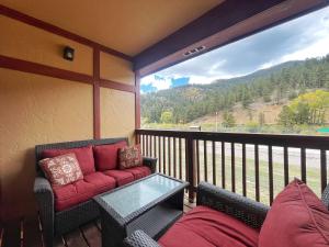 un balcone con divano, tavolo e ampia finestra di Valley Condo 111 - Dancing Bear Retreat - Creekside - WiFi - Hot Tub - Fireplace - Washer - Dryer - Playground a Red River