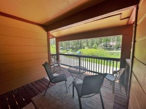 una veranda protetta con sedie e un tavolo di Valley Condo 112 - Creekside - WiFi - Pet Friendly - Hot Tub - Fireplace - Washer - Dryer - Playground a Red River Altre 9 foto