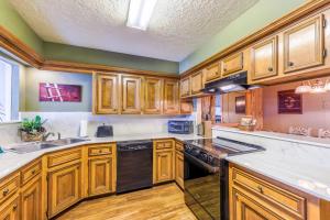 una cucina con armadi in legno e lavastoviglie nera di Valley Condo 119 - Creekside - WiFi - Hot Tub - Fireplace - Washer - Dryer - Playground a Red River