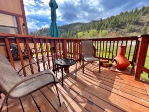 una terrazza con sedie, tavolo e ombrellone di Valley Condo 120 - Creekside - WiFi - Pet Friendly - Hot Tub - Fireplace - Washer - Dryer - Playground a Red River