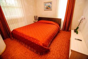 a bedroom with a bed with an orange comforter at Pajūrio Sodyba in Šventoji