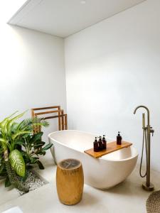 a white bath tub in a bathroom with plants at Neptune Studios Luxury Villa with Pool Gym & Recovery in Kuta Lombok +35 photos
