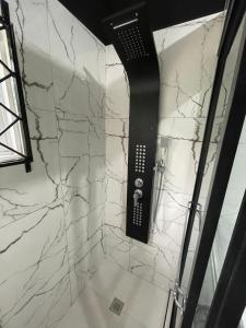 e bagno con pareti in marmo bianco e doccia. di Hide Away From Home a May Pen