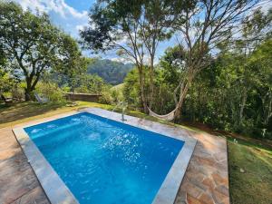 a swimming pool in the yard with a water fountain at Casa Da Floresta Cercada com Piscina in Santo Antônio do Pinhal