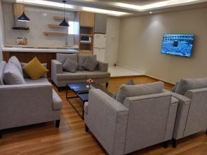 a living room with three couches and a table at فيجن للشقق المخدومة ــ اقتصادي in Buraydah
