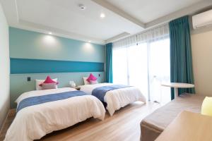 two beds in a room with blue walls and windows at Blue Cove Terrace in Miyako Island