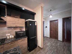 a kitchen with a black refrigerator in a room at 2&1 BR Apartment at Jikia's Green Complex-Central Tbilisi in Tbilisi City +11 photos