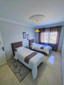 a bedroom with two beds and a window at Appartement plus que parfait in Tangier