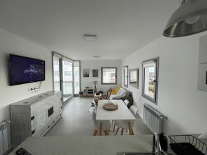a white living room with a table and a tv at Torres al Mar in Monte Hermoso