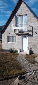 a brick house with a white door and a balcony at Casa del Lago in Bialet Massé