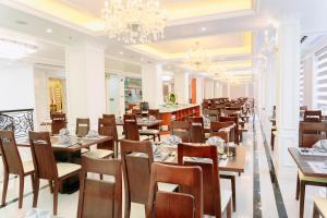 a restaurant with wooden tables and chairs and a chandelier at SC Luxury Hotel in Ha Long