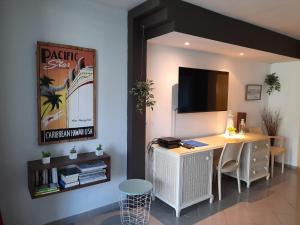 een kamer met een bureau en een tv aan de muur bij ILET BLEU studio cosy RDC vue mer et jardin - Accès direct plage in Le Gosier