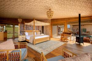a bedroom with a canopy bed and a living room at One Nature Mara River in Serengeti National Park +18 photos