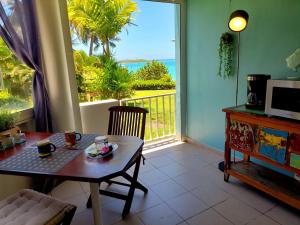 een woonkamer met een tafel en uitzicht op de oceaan bij ILET BLEU studio cosy RDC vue mer et jardin - Accès direct plage in Le Gosier +19 foto's