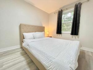 a bedroom with a white bed with a window at New 3 Bedroom Bungalow Ground Floor with BBQ Patio in Richmond Hill