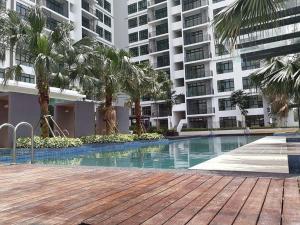 a swimming pool in front of a building with palm trees at Citywoods Apartment Next to Thistle hotel,Hospital Sultanah Aminah,Ciq custom3km by YHA in Johor Bahru
