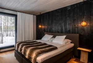 a bedroom with a bed with a wooden wall at Wilderness Hotel Juutua in Inari