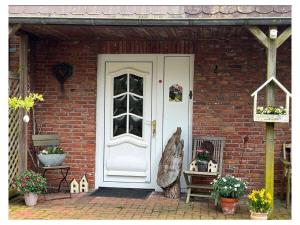 a white door of a brick house with flowers at LUV and LEE Comfortable holiday residence in Wesselburenerkoog