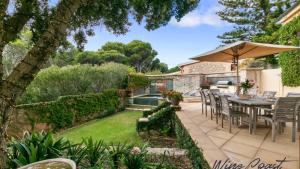 a patio with a table and chairs and an umbrella at Alton House By Wine Coast Holidays in Port Willunga
