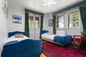 Chalet Ecureuil - Happy Rentals في شامونيه مون بلان: غرفة نوم بسريرين واريكة زرقاء