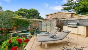 a patio with two lounge chairs and a swimming pool at Alton House By Wine Coast Holidays in Port Willunga