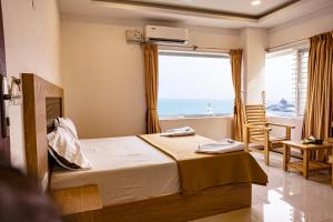 a bedroom with a bed with a view of the ocean at Hotel Sea Land in Kanyakumari