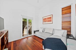 a living room with a couch and a tv at Straddie Glasshouse by Discover Stradbroke in Point Lookout