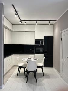 a white kitchen with a table and chairs in it at Sholpan city comfort in Almaty