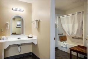 a bathroom with a sink and a tub and a mirror at Sandia Peak Inn Old Town ABQ, a Howard Johnson by Wyndham in Albuquerque +34 photos