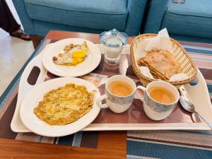 a tray with two plates of food and two cups of coffee at Holidazzle Lodge Islamabad in Islamabad
